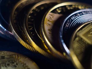 Closeup shot of gold and silver coins scattered on a surface illuminated with bright light
